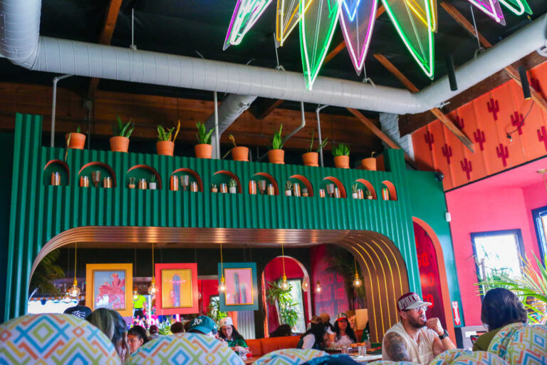 Vibrant dining room at Pig Latin in Elk Grove featuring colorful décor, tropical plants, and modern Mexican-inspired design.