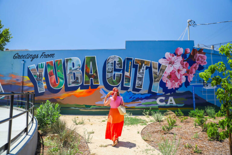 Visitor walking toward the Greetings from Yuba City mural in downtown Yuba City, California.