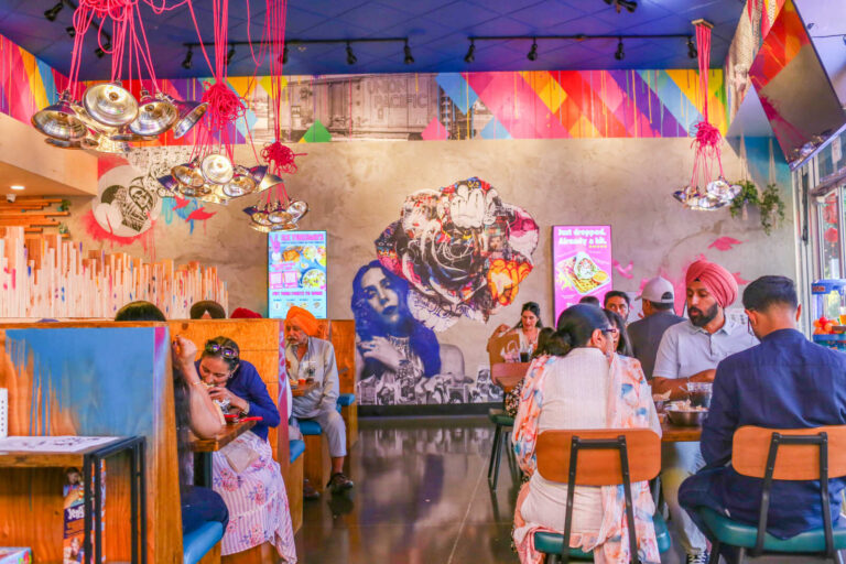 Bright, colorful dining room inside Spitz in Roseville featuring vibrant murals, modern lighting, and guests enjoying Mediterranean street food.