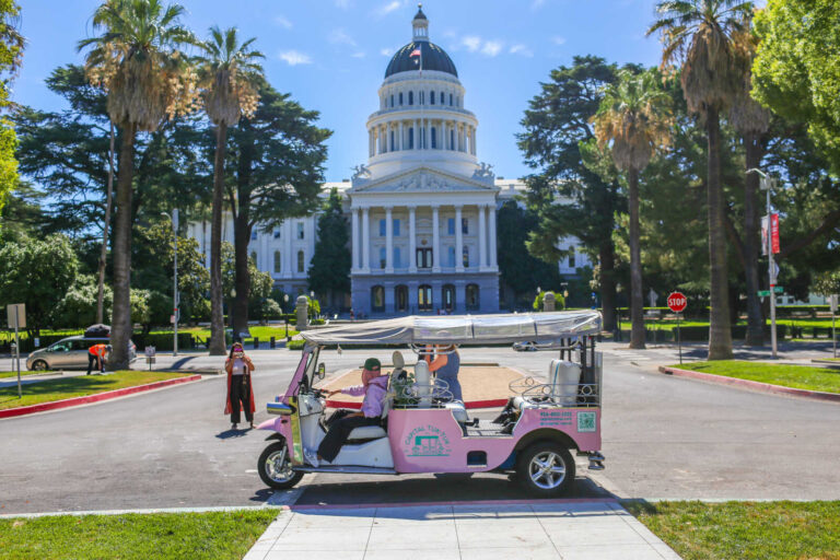 Pink Capital Tuk Tuk parked in front of the California State Capitol in Sacramento.